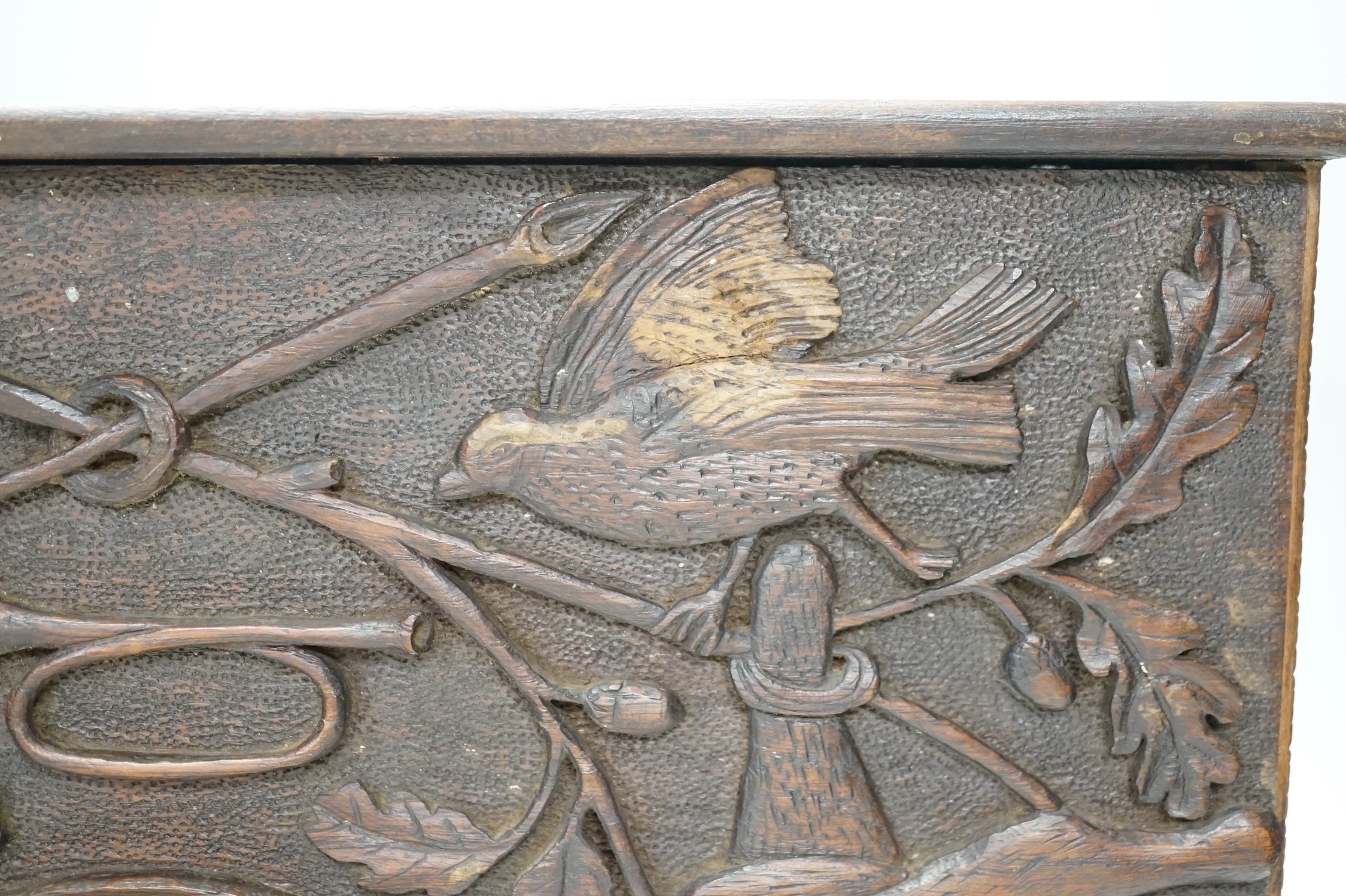 A late 19th century / early 20th century folk art carved oak cased clock, decorated with hanging dead game amongst oak sprigs and acorns, 34x39cm